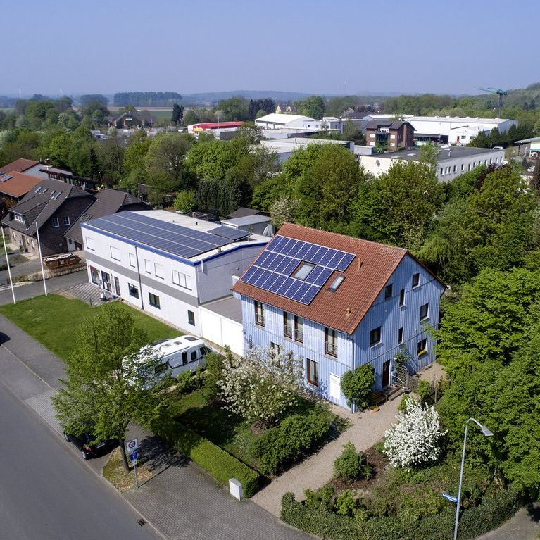 Glücklicher Mann mit Brille lächelt vor historischer Architektur im Hintergrund.