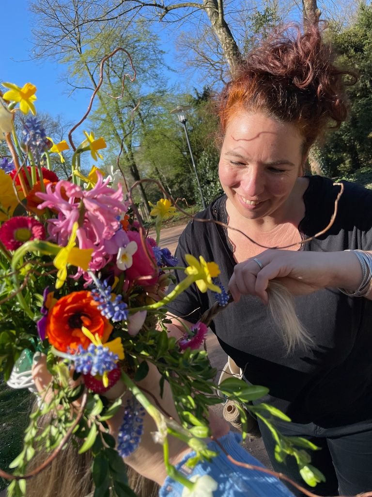 Frau mit roten Haaren arrangiert bunte Blumenstrauße im Freien.
